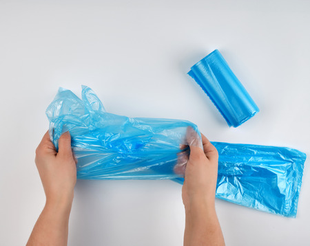 blue plastic garbage bag in hands on a white background, top view