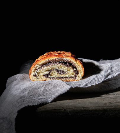 baked roll with poppy seeds on gray linen napkin, dark backgroundの写真素材