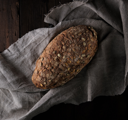 baked oval bread made from rye flour with pumpkin seeds on a gray linen napkin, top viewの写真素材