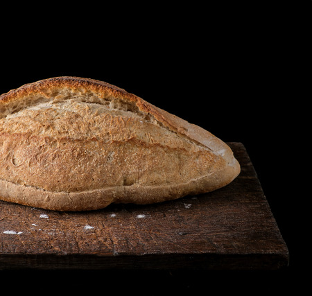 white wheat flour baked crisp bread on a wooden board, black background