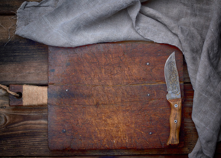very old empty brown wooden cutting board with handle and kitchen napkin, top viewの写真素材