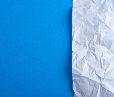 crumpled blank white paper on a blue background, copy spaceの写真素材