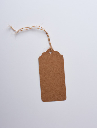 Empty paper rectangular brown tag on a rope, white background, sales conceptの写真素材