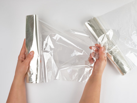 Plastic food wrap for baking products in the oven in women's hand, view from the top, white...