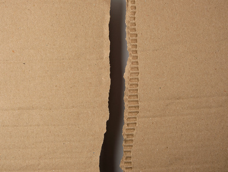 torn in half brown sheet of paper from under the box, a slot in the middle, full frame