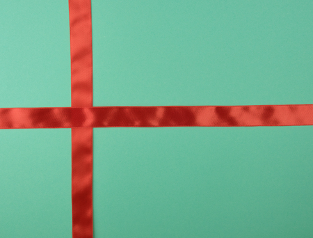 red satin ribbon cross to cross on green background, close upの写真素材