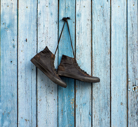 pair of black textile sneakers hanging on a blue wooden wallの写真素材