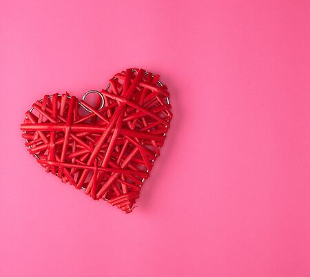wicker red hearton a pink background, holiday background , copy space
