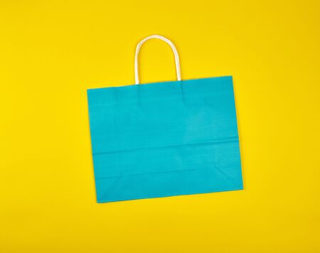 rectangular blue paper shopping bag with a white handle on a yellow background, flat layの写真素材