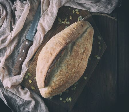 baked crisp oval bread and vintage knife, top view