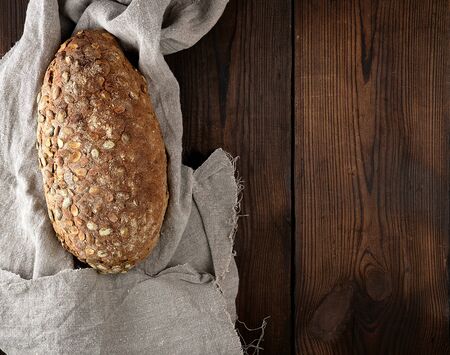 baked oval bread made from rye flour with pumpkin seeds on a gray linen napkin, top view, copy spaceの写真素材