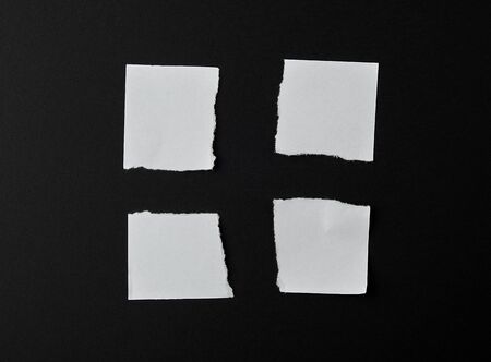 torn into four pieces empty white sheet of paper on black background, close up