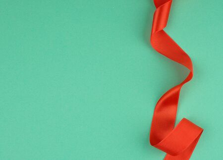 twisted red silk ribbon, green background, top view, copy spaceの写真素材