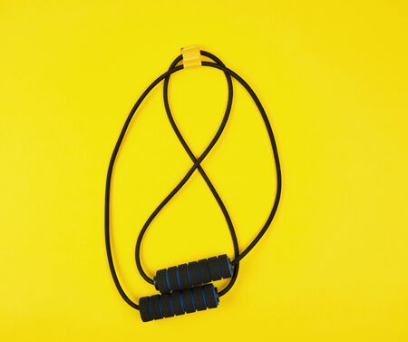 black trainer hand expander on a yellow background, flat lay