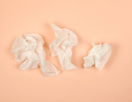 crumpled white paper napkins on a beige background, top view