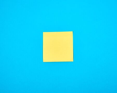 yellow empty paper square stickeron blue background, copy spaceの写真素材