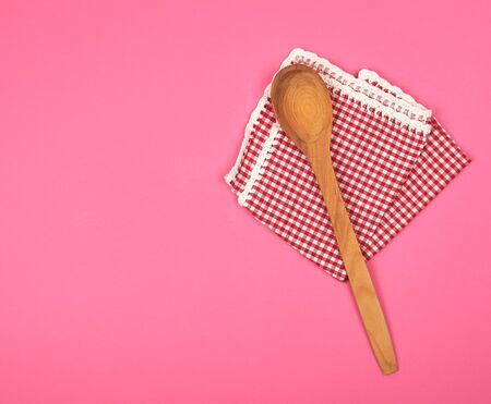 wooden spoon on a red kitchen towel, pink background, copy spaceの写真素材