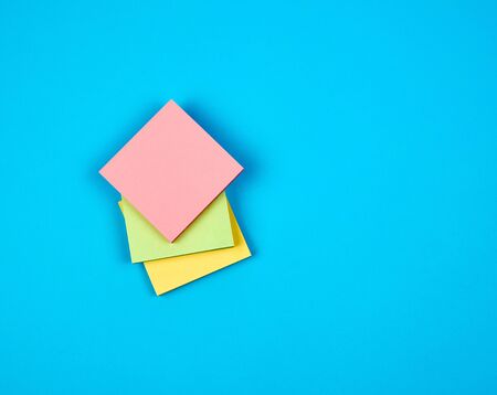 multicolored empty paper square stickers on blue background, copy spaceの写真素材