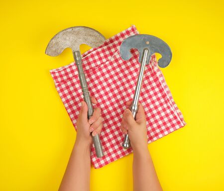 two hands holding vintage sharp kitchen knives for meat and vegetables, yellow backgroundの写真素材