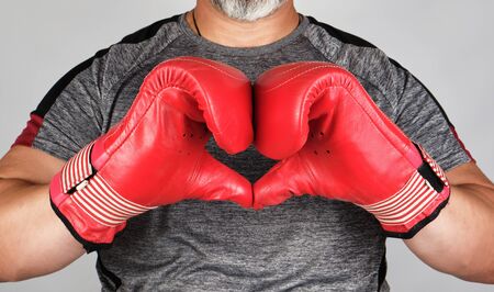 athlete in red boxing leather gloves shows hands with a heart symbol, white backgroundの写真素材