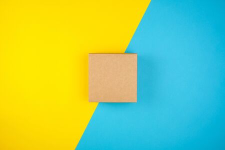 square brown gift box on a yellow-blue background, top view
