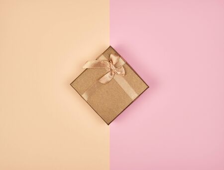 closed square box with a bow on an abstract colored background, top viewの写真素材
