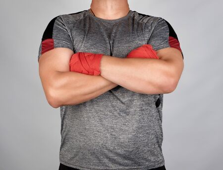male athlete crossed his arms over his chest, brushes rewound with a red elastic bandage, white backgroundの写真素材