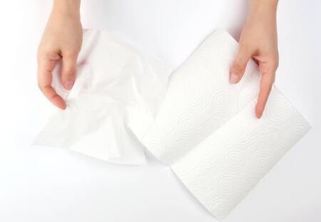 two female hands holding a clean white paper napkin for face and body, white backgroundの写真素材