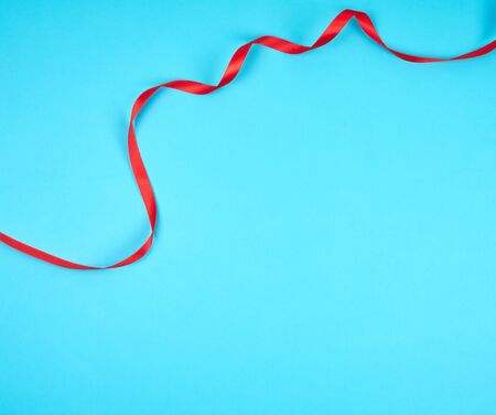 twisted red silk ribbon, blue background, top view, copy spaceの写真素材