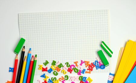 school supplies: multicolored wooden pencils,  notebook, colored paper and  blank white sheet in a...
