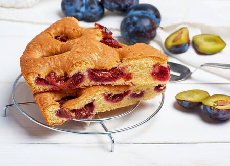 slices of biscuit plum cake on a white wooden board and fresh fruits, top viewの写真素材