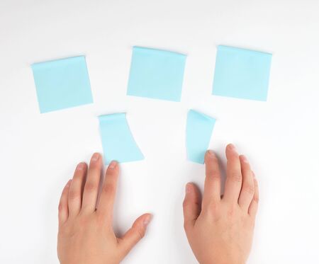 lot of blue stickers on a white background and two female hands pointing at them, conceptual...