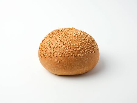 baked whole round bun with sesame seeds made from white wheat flour on a white backgroundの写真素材