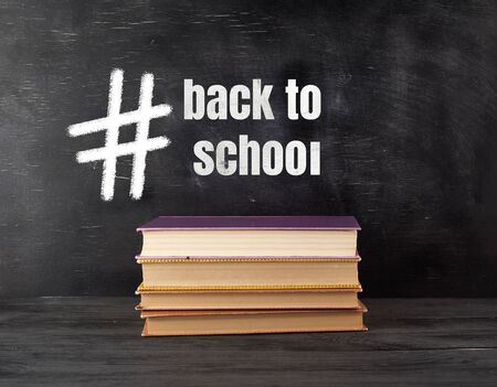 four closed books with yellow sheets on a black chalk board background, back to school conceptの写真素材