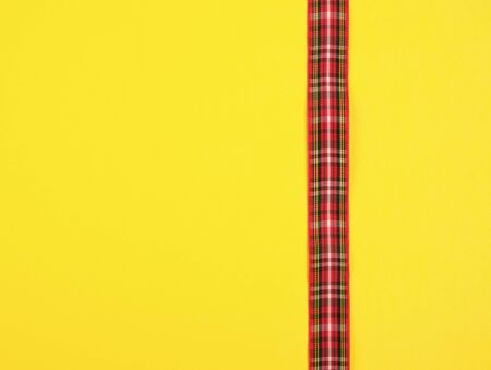 red ribbon in the box on a yellow background, festive backdrop, copy spaceの写真素材