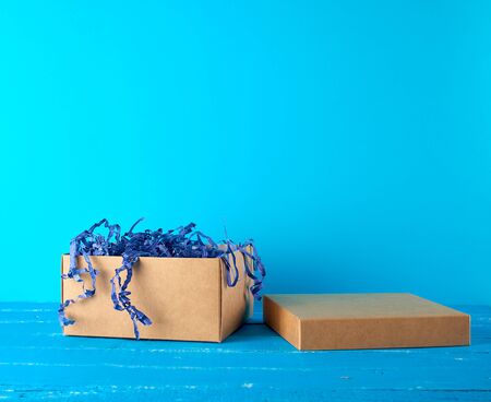 open empty brown craft box on a blue wooden background, holiday backdrop