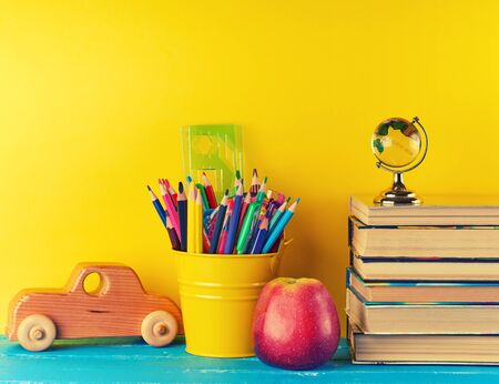 background back to school with children's stationery pencils, books, apple, glass globe on a blue backgroundの写真素材