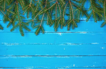 green branches of needles on a blue background from shabby boards, festive Christmas background,...