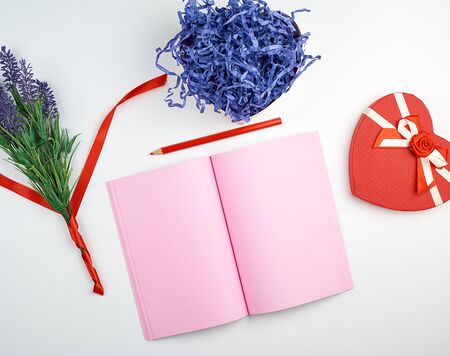 open notebook with blank pink pages, wooden red pencil and a bouquet of lavenders on a white...