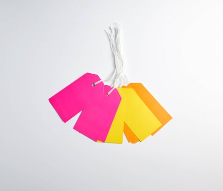 rectangular paper pinks, yellow and orange tags for things on a white rope, white backgroundの写真素材