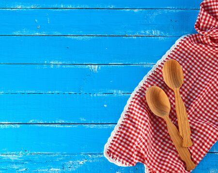 wooden spoon on a red kitchen towel, blue background, copy space