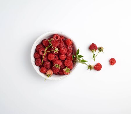 ripe red raspberries in a wooden white plate on a white background, top viewの写真素材