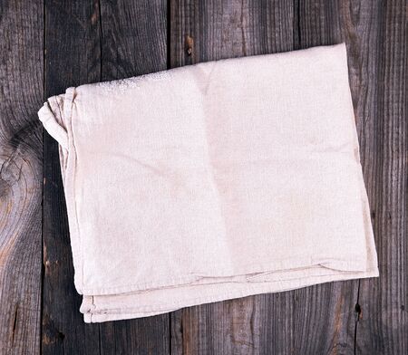 folded gray linen kitchen  towel on wooden background, top view