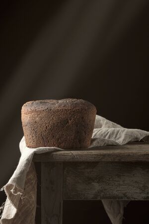 baked rye bread on a gray linen napkin, old wooden table, copy space