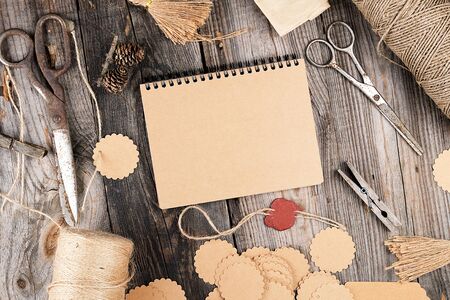 notepad with brown empty sheets on a gray wooden table, next to it are a rope, paper tags and...