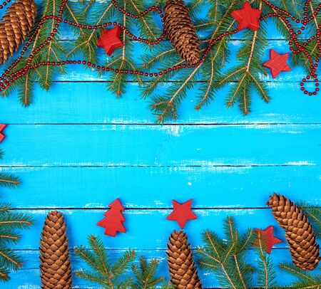 green branches of needles and yellow Christmas garland, red decorations on a blue wooden background from boards, copy spaceの写真素材