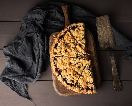 half plum pie crumble on a brown wooden cutting board, top viewの写真素材