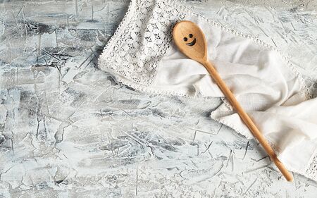 wooden spoon with a funny smile lies on a vintage white textile towel, gray backgroundの写真素材