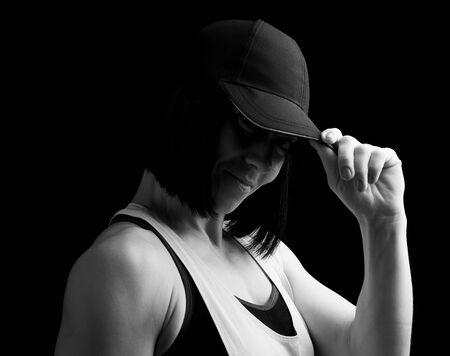 portrait of an adult girl with black hair holding a cap on her head, black and white toningの写真素材