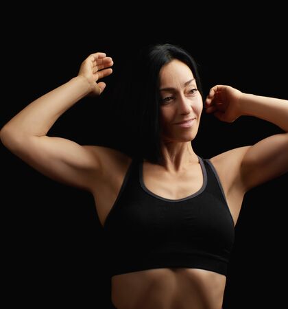 Adult girl with a sports figure in black bra standing on a dark background, muscular body, black hairの写真素材